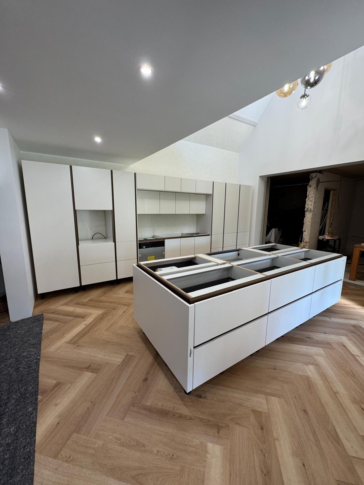 Cuisine blanche avec îlot central et parquet chevrons